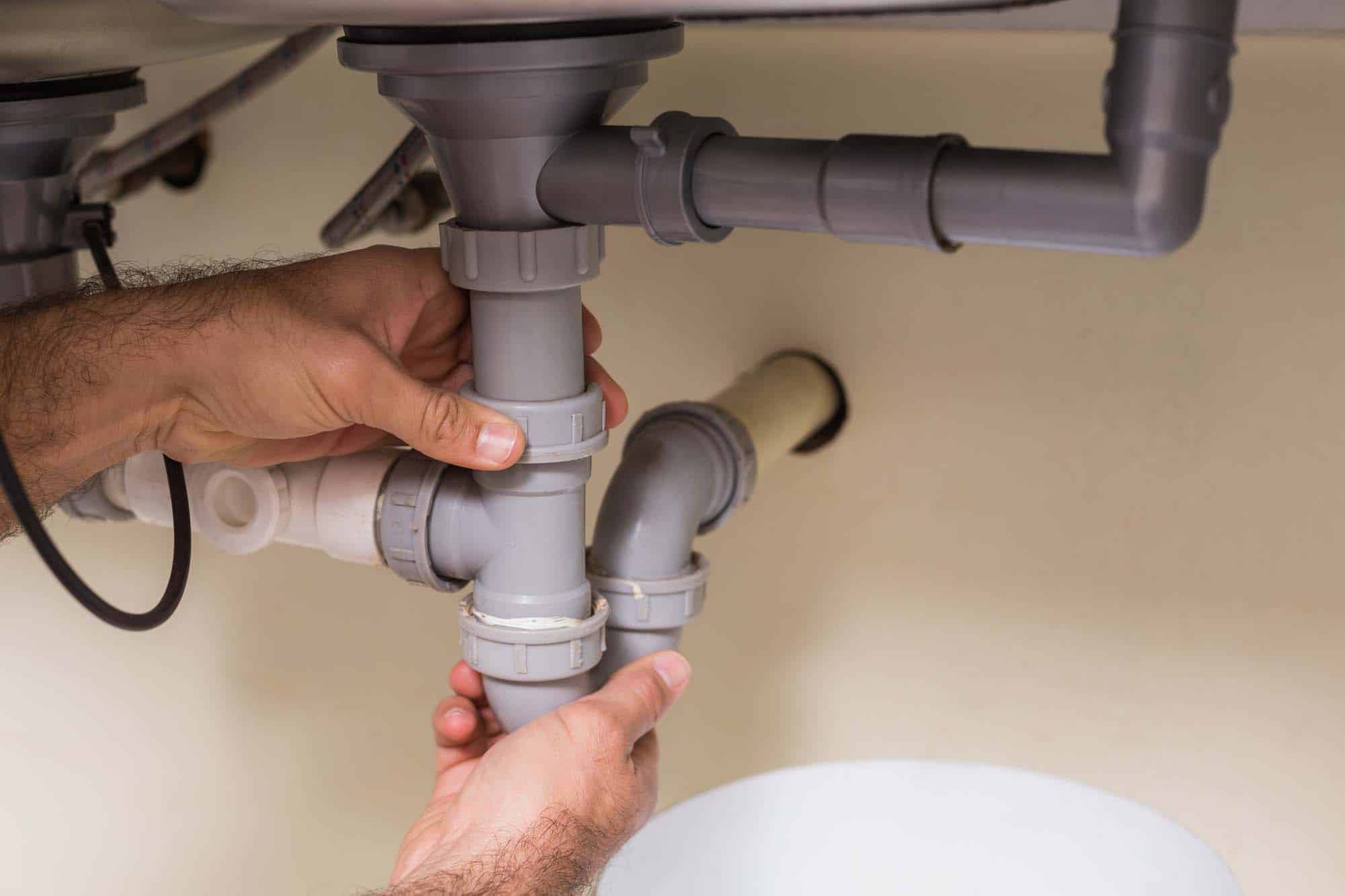 Plumber fixing under the sink in the kitchen